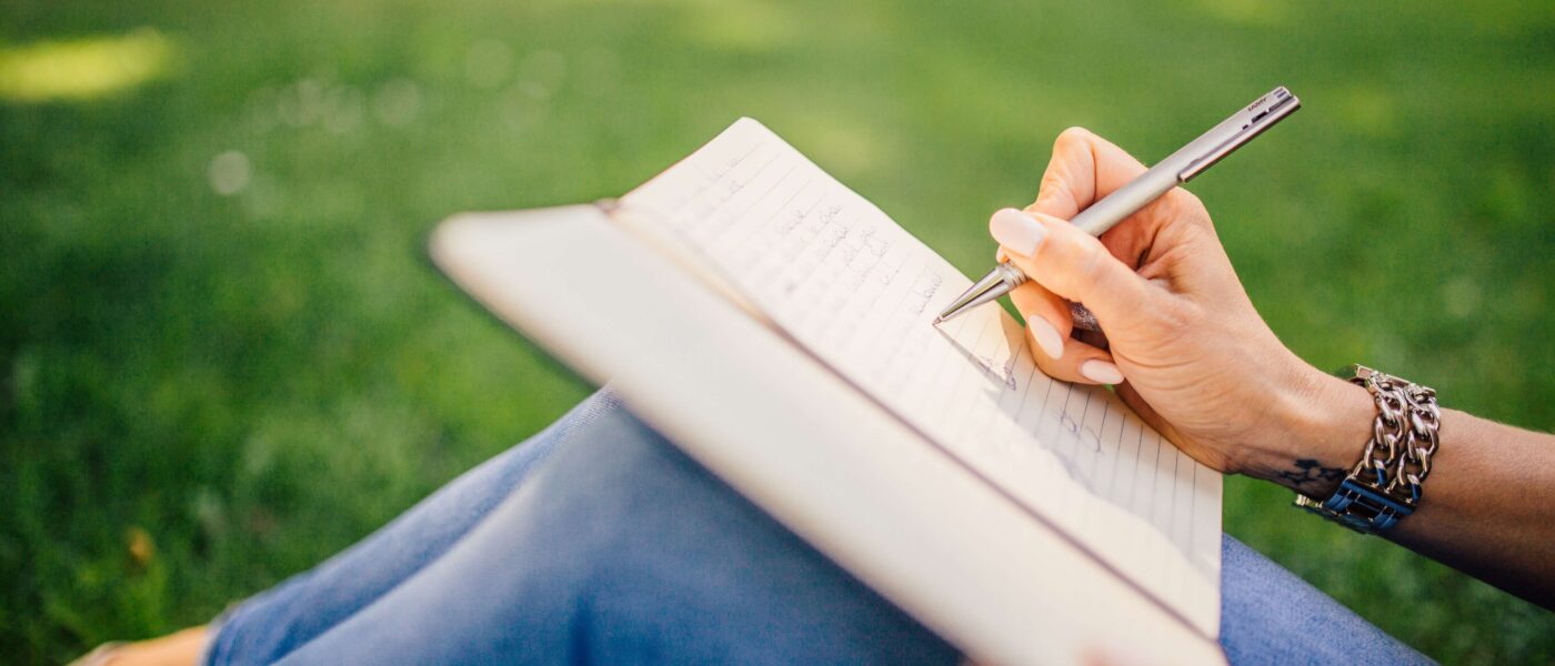 Una persona escribiendo en un cuaderno en un parque tranquilo