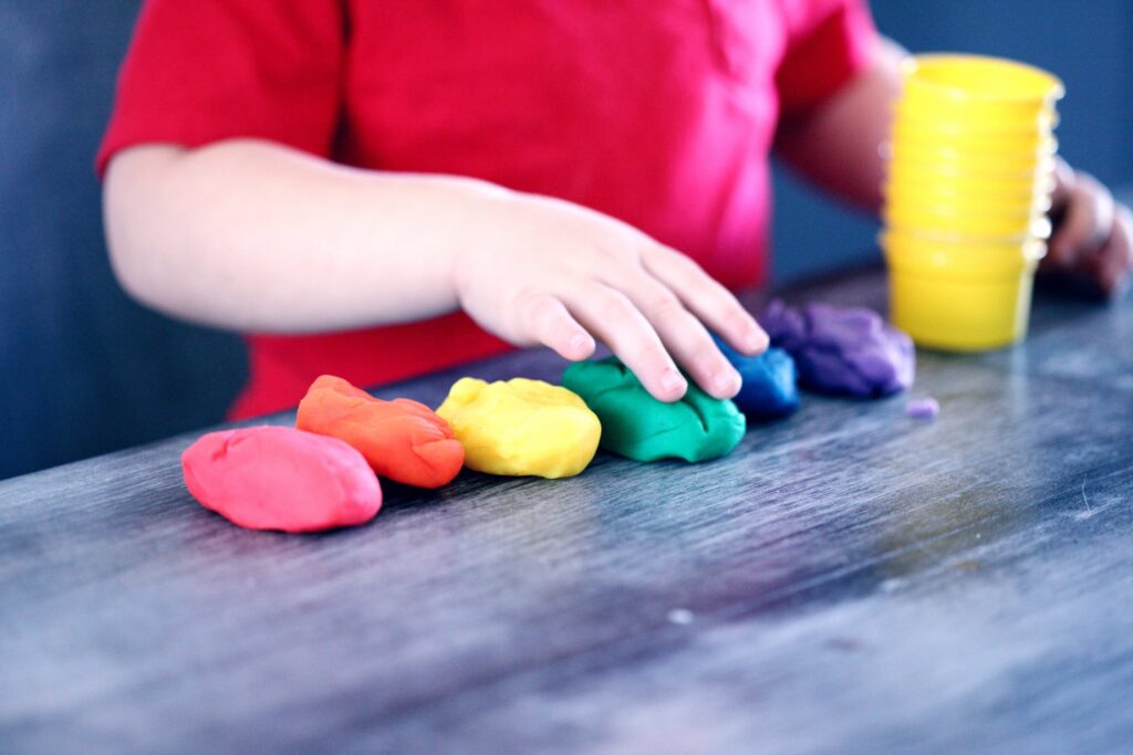 Manos de niño jugando con plastilina de colores