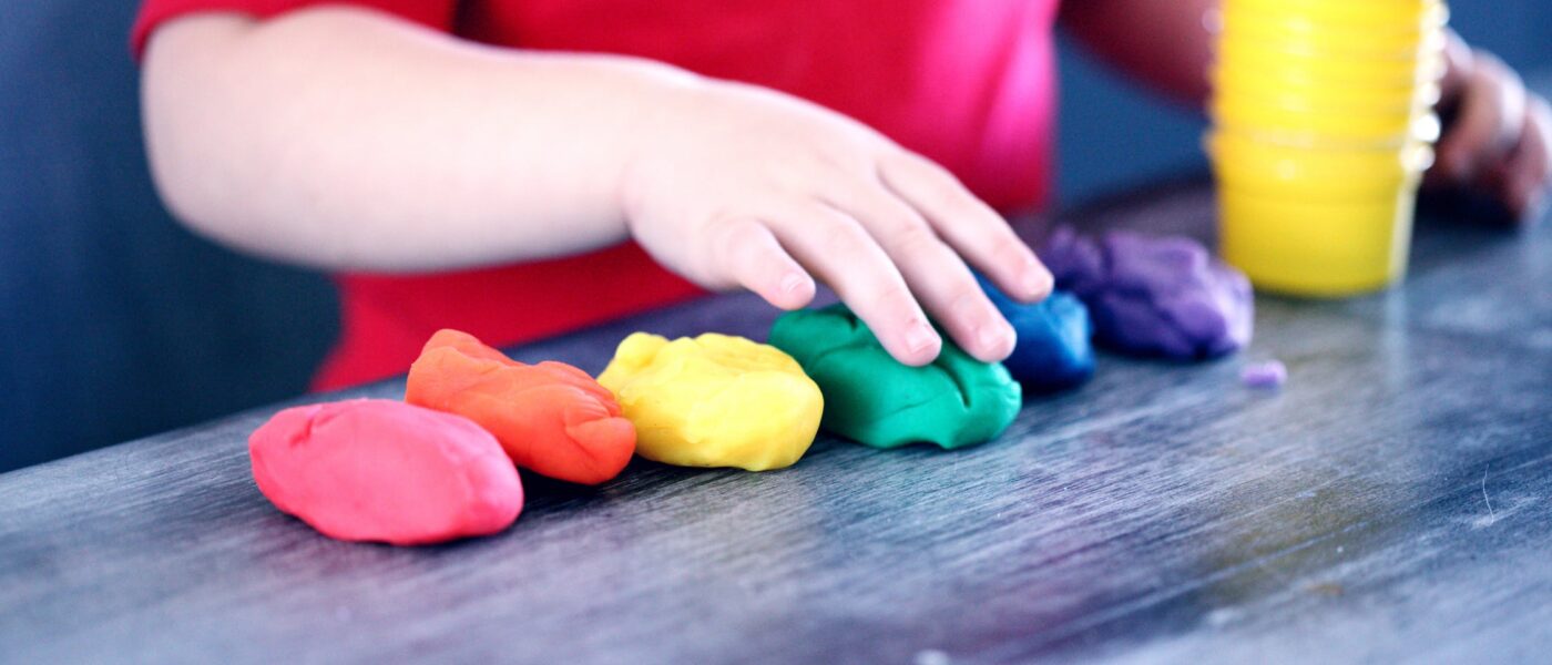 Manos de niño jugando con plastilina de colores