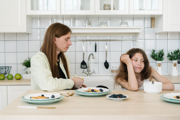 Madre y adolescente sentadas a la mesa durante una comida en un entorno familiar.