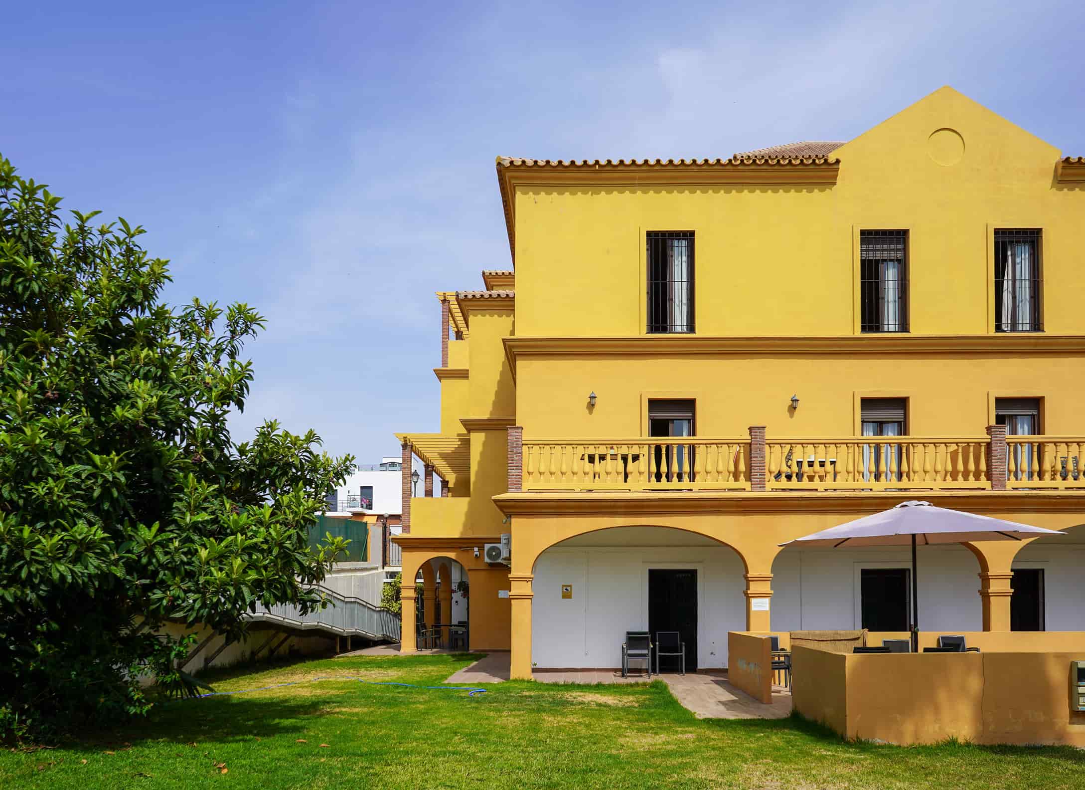 Edificio Ita Torre del mar, color amarillo y rodeado de un jardin
