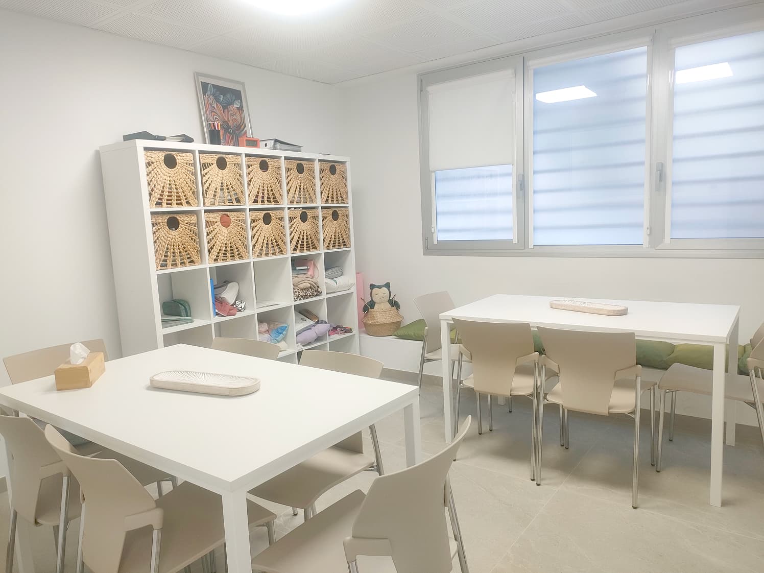 Sala de estar con mesas de comedor y una estantería cuadriculada