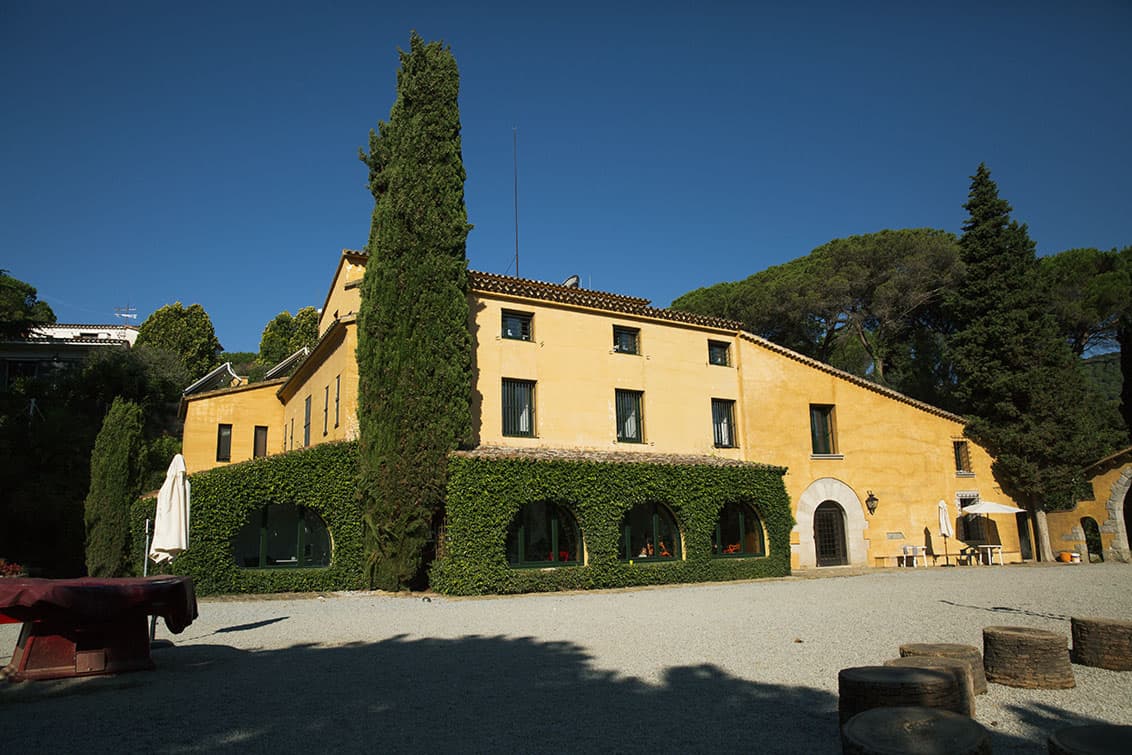 Casa de estructura clásica y fachada beige rodeada de vegetación
