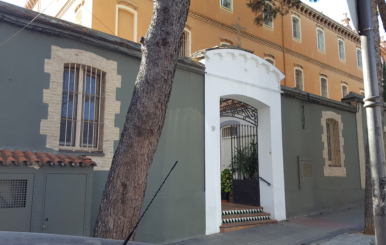 Fachada de un centro educativo con entrada principal y árboles en el exterior