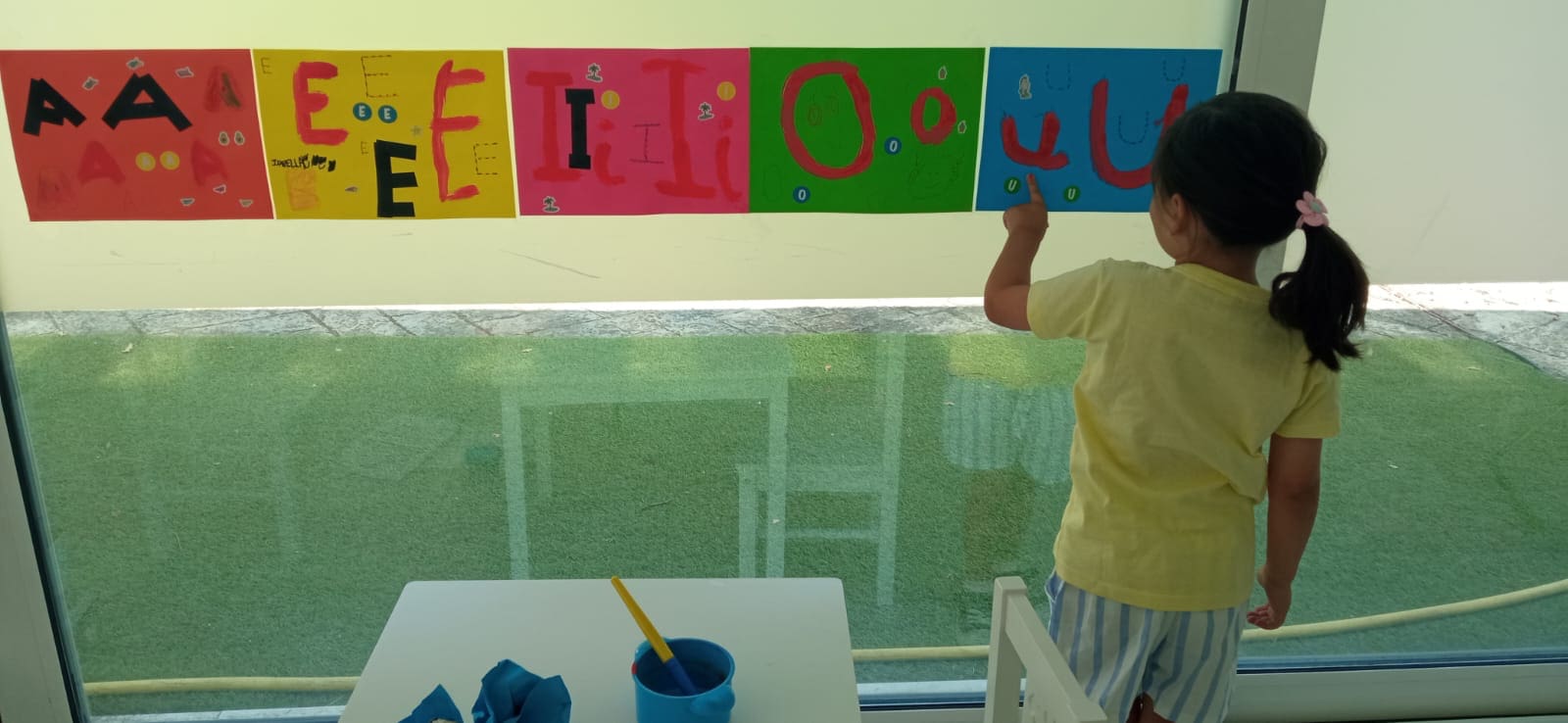 Niña señalando letras de colores en una actividad educativa