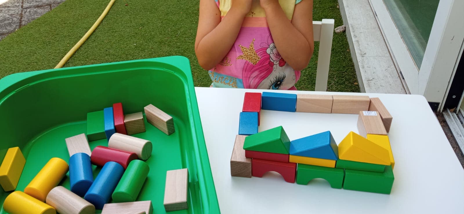 Niña jugando con bloques de construcción de colores en una mesa