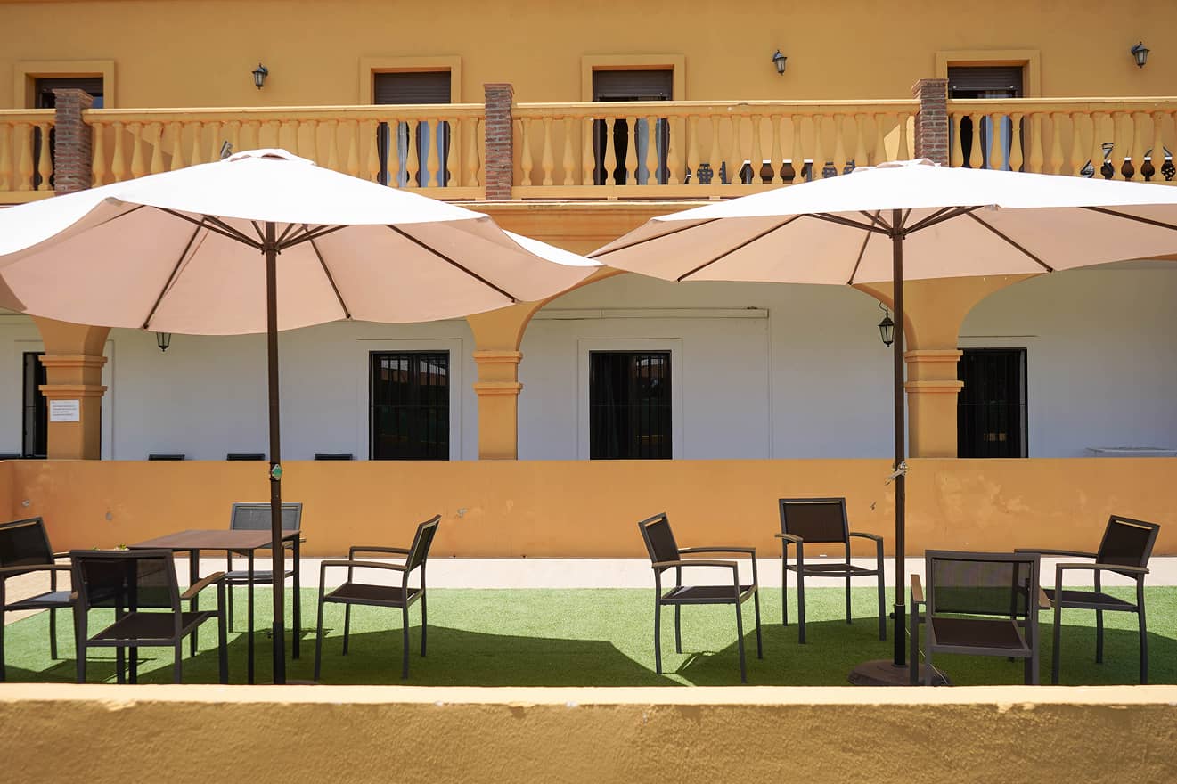 Zona de terraza exterior de las instalaciones con sombrillas y césped artificial