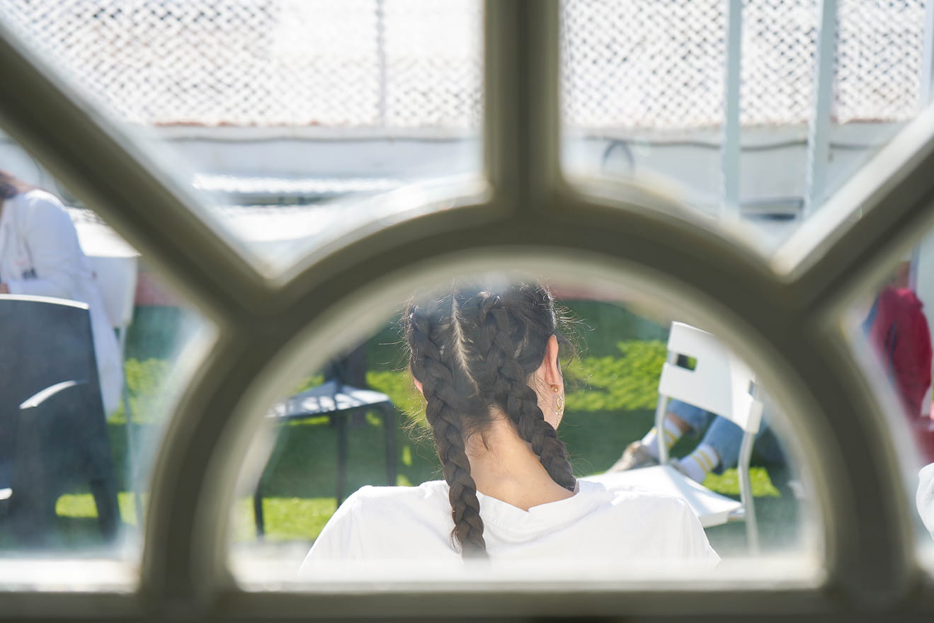 Joven sentada en el exterior de Ita Vidrio vista a través de una ventana